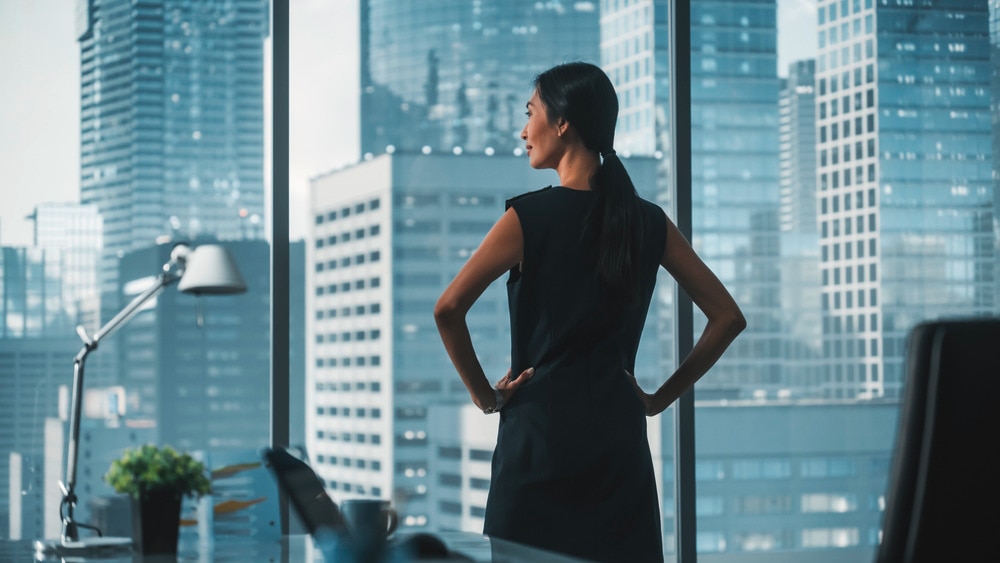 Professional woman doing the Wonder Woman pose in her office.
