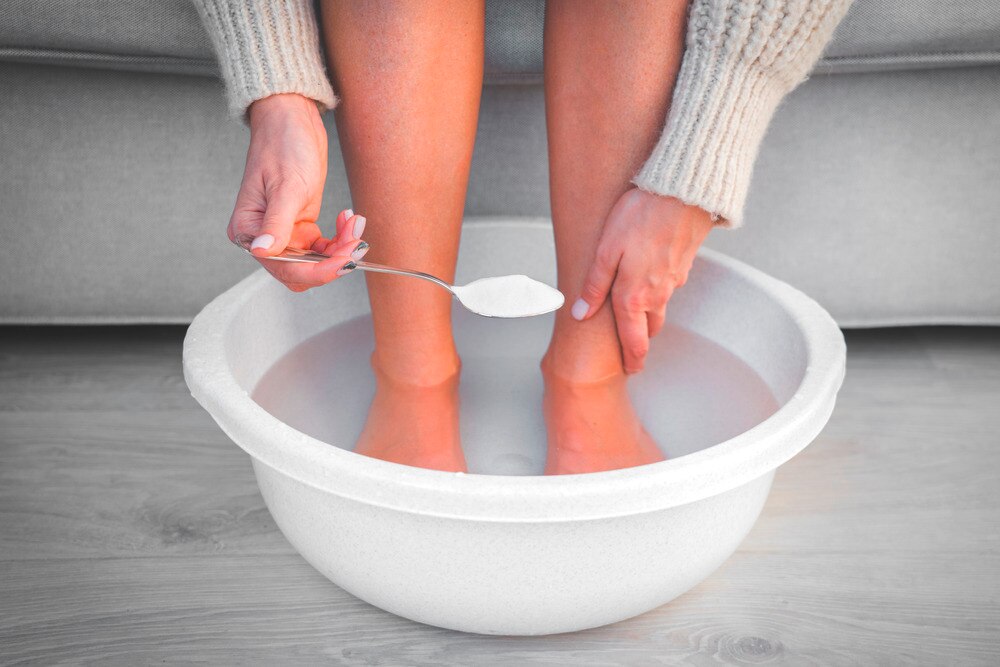 Woman putting baking soda in her foot bath.