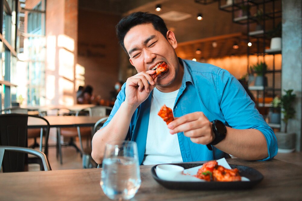 Man eating chicken wings BBQ at a restaurant.
