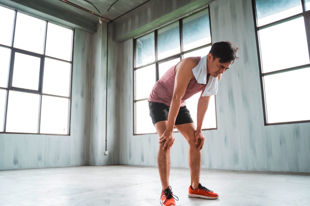 A tired man with a towel on his nape taking a break from exercising