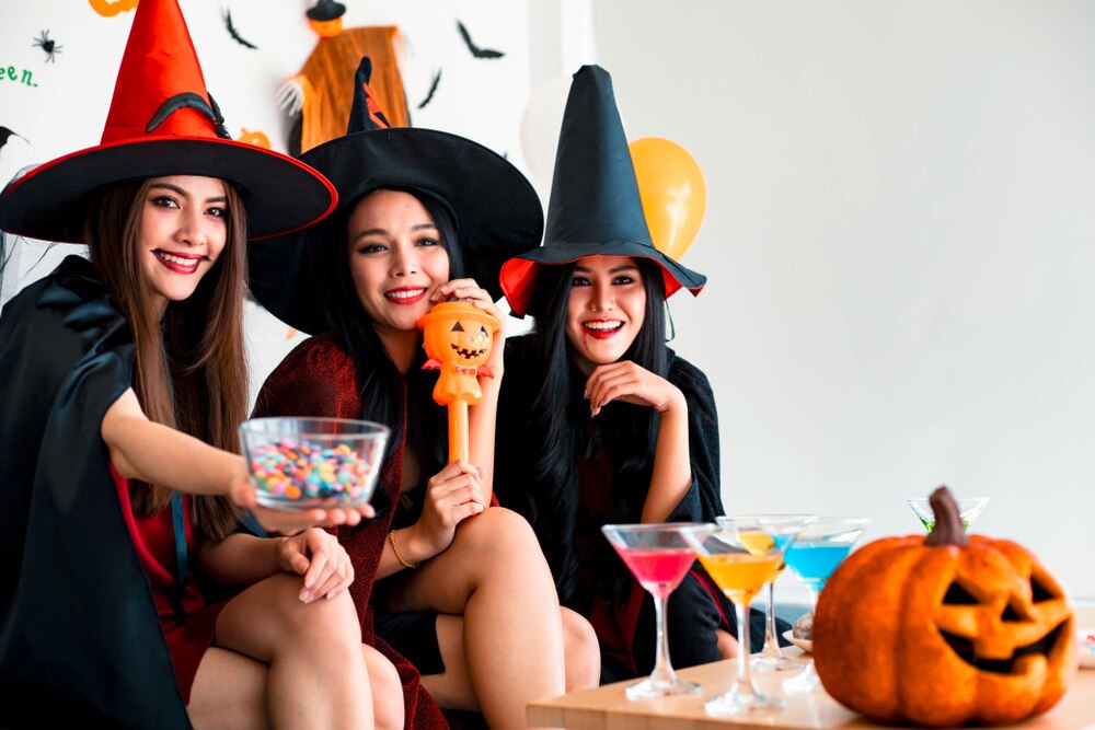 Asian women in with costumes drinking cocktails and eating candy.