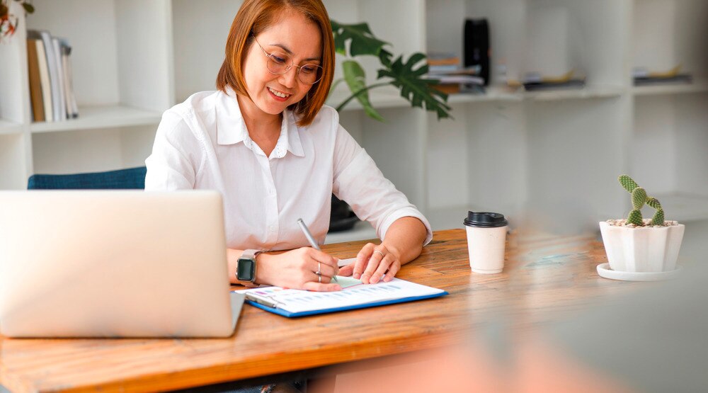 Middle-aged woman with colored hair working behind a desk.