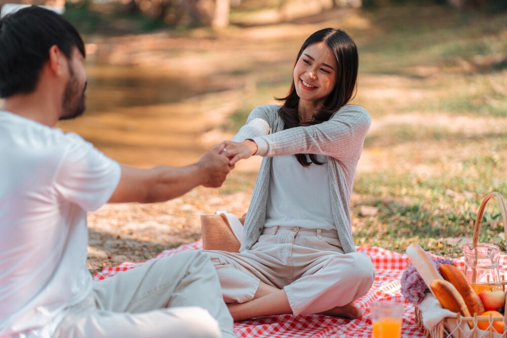 Man and woman holding hands and enjoying a romantic picnic.