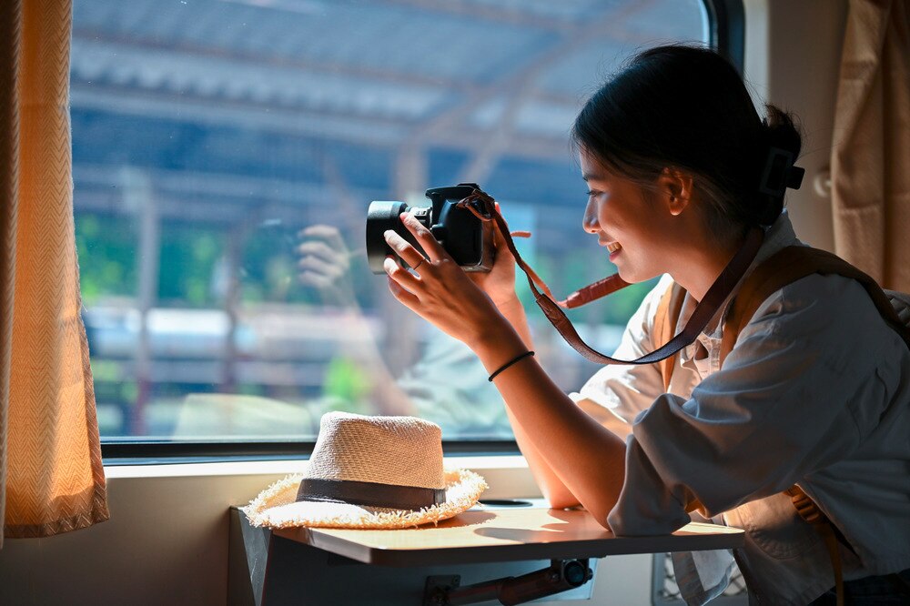 Woman taking photo with her camera while sitting inside a train.