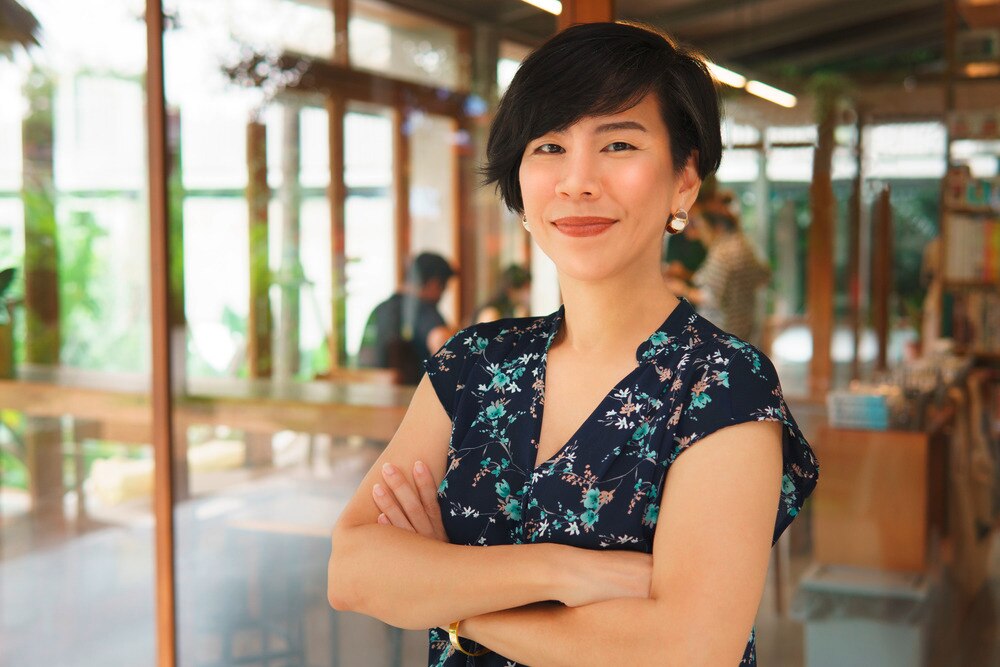 Woman with short hair and black top crossing her arms and smiling to the camera.