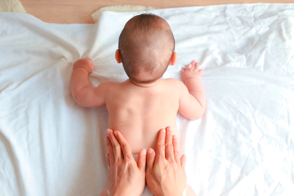 A parent rubbing a baby’s back.