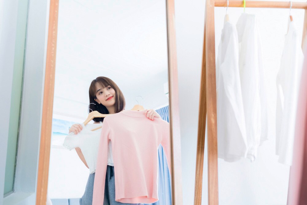 A woman trying on clothes in front of a mirror