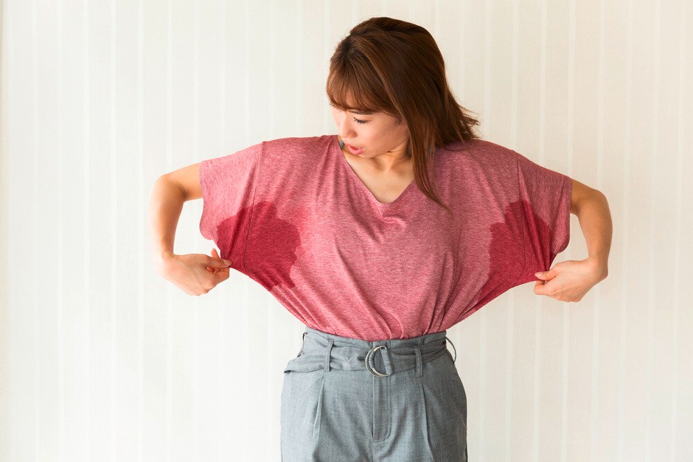Asian woman checking out sweat stains on her clothes