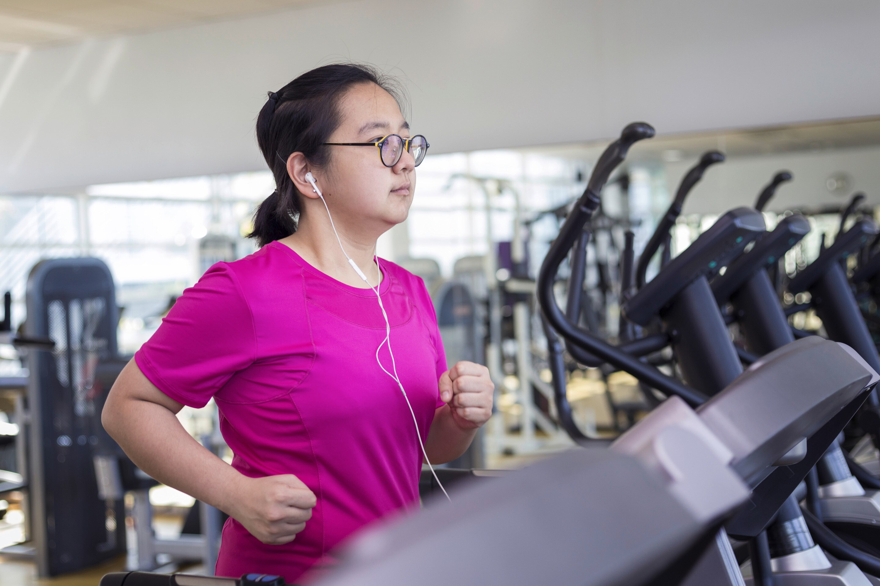 A woman with glasses on a treadmill