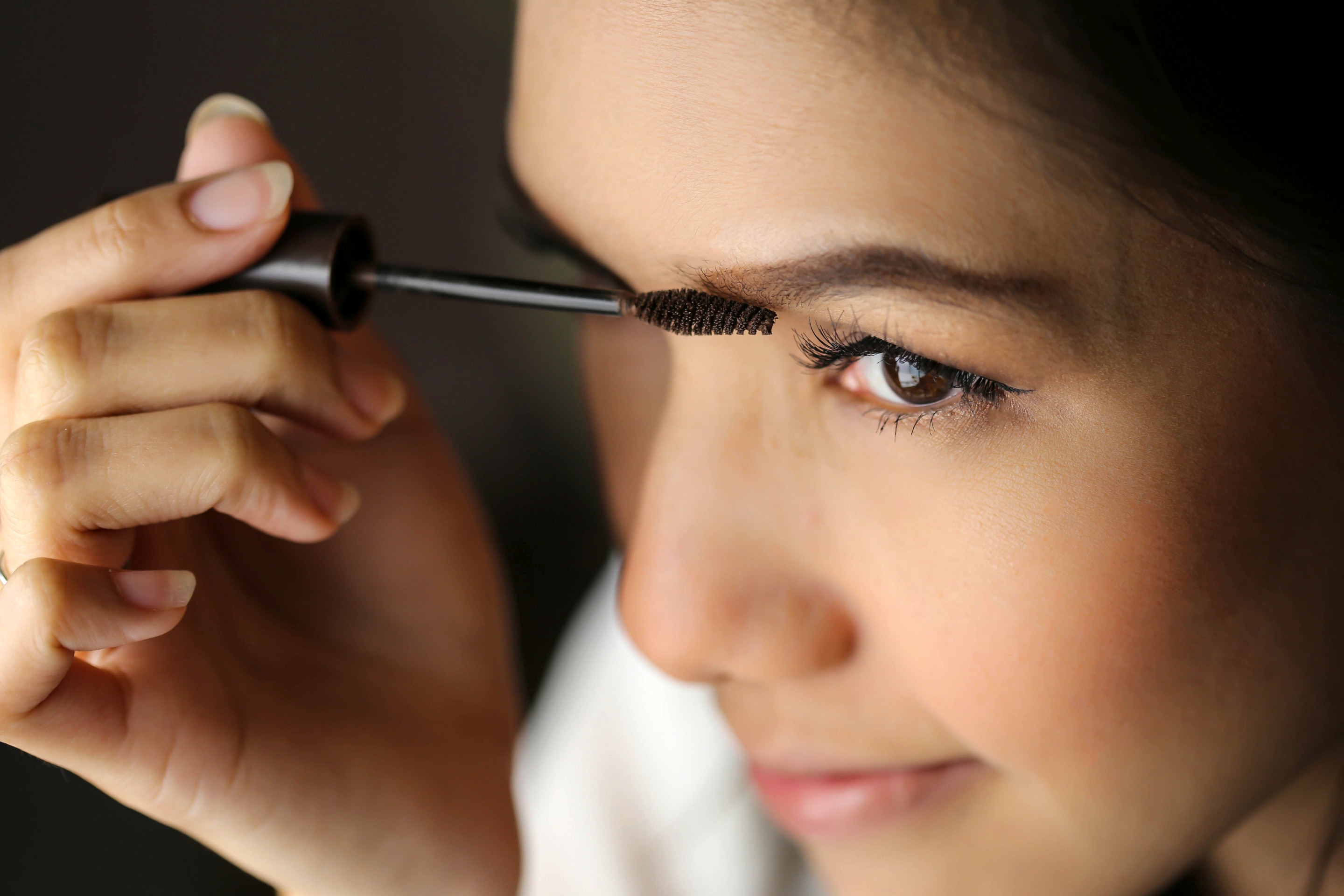 Asian woman applying mascara