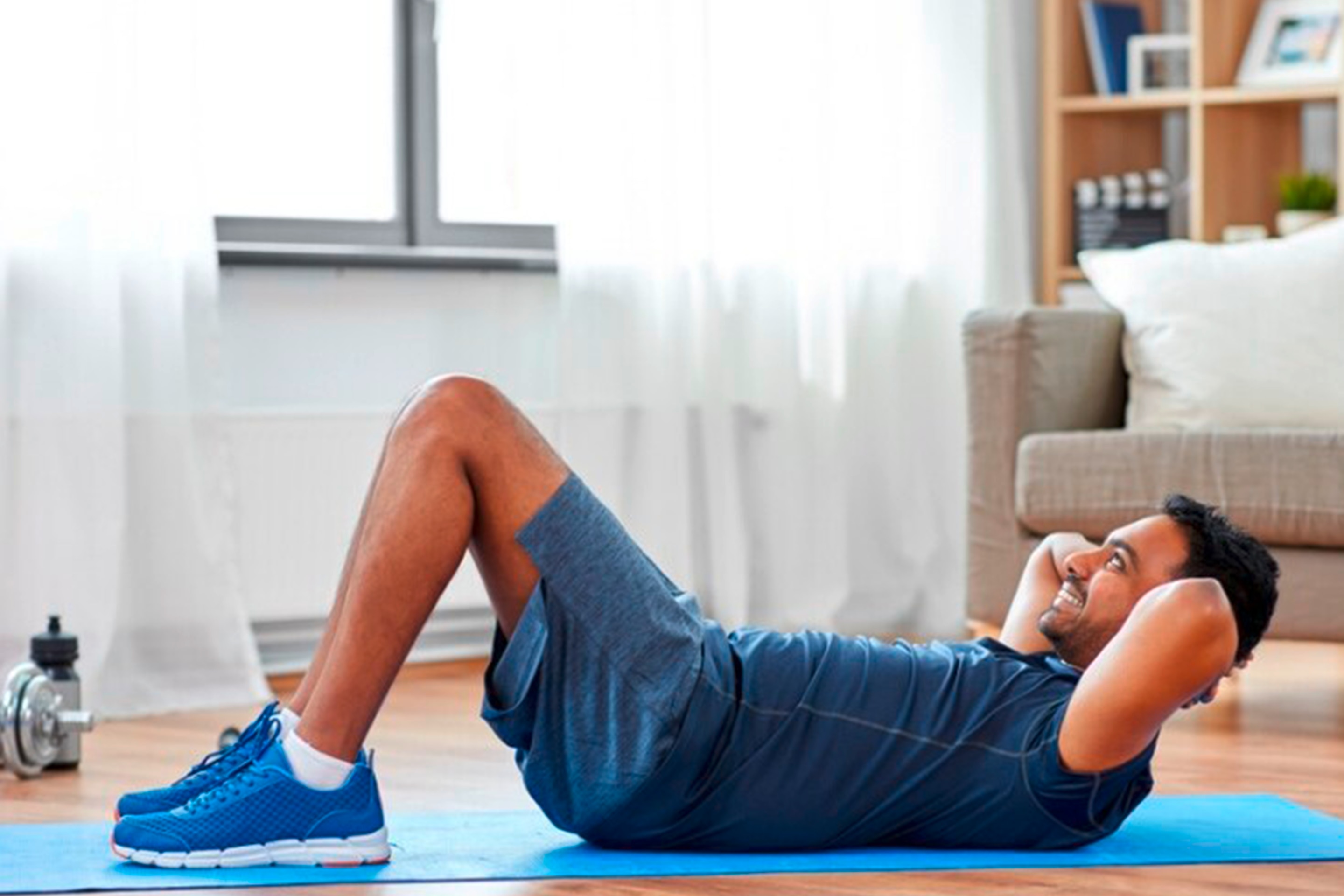 pria sedang melakukan gerakan workout di rumah berupa sit up
