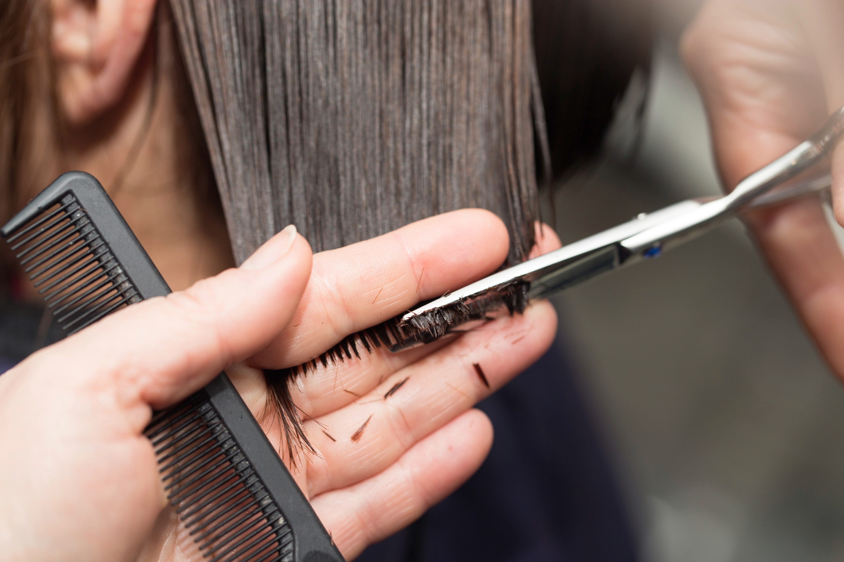 Closeup of woman’s hands cutting hair at a salon