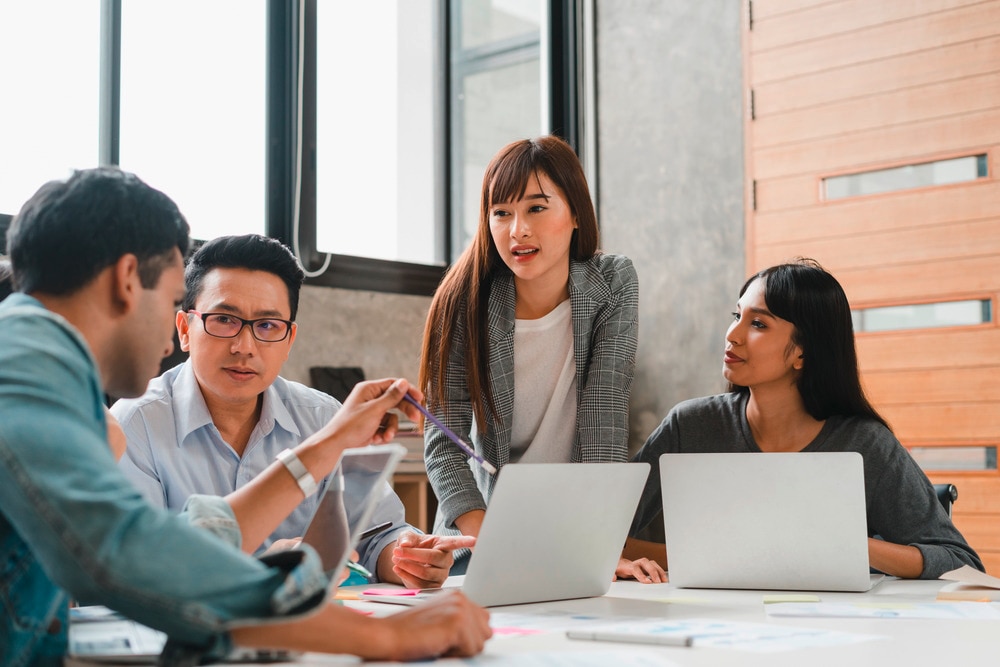 A group of multiracial workers working and talking together in a meeting room.