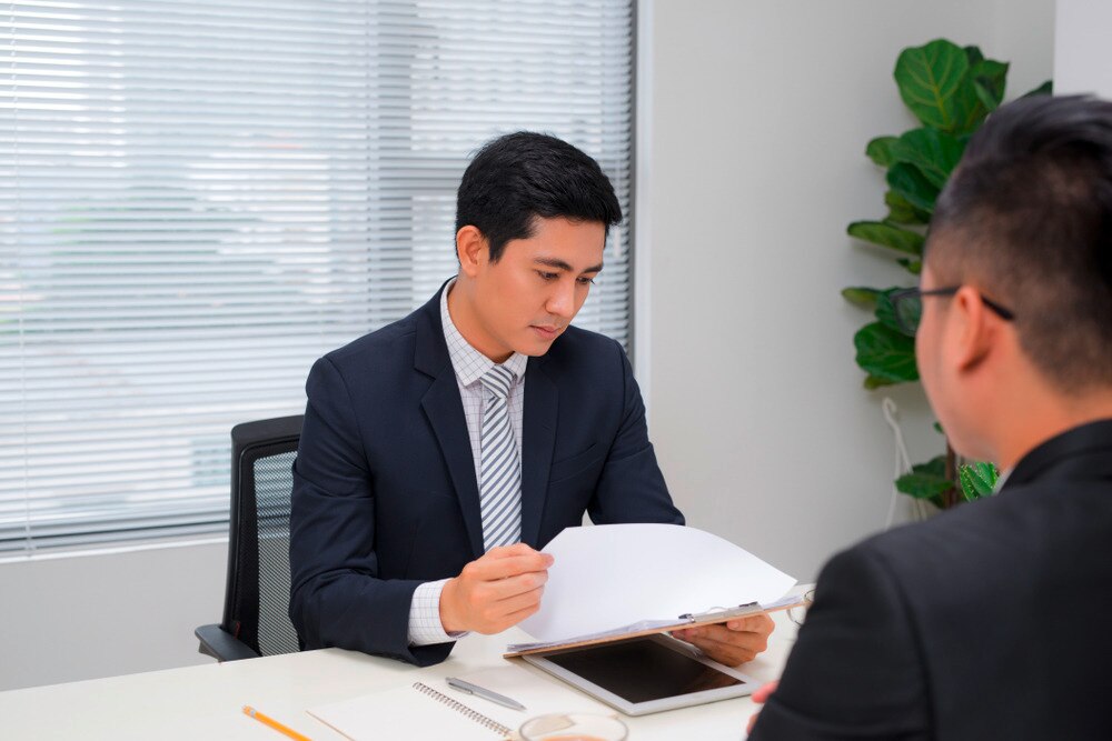 A manager reviewing papers in front of a man.
