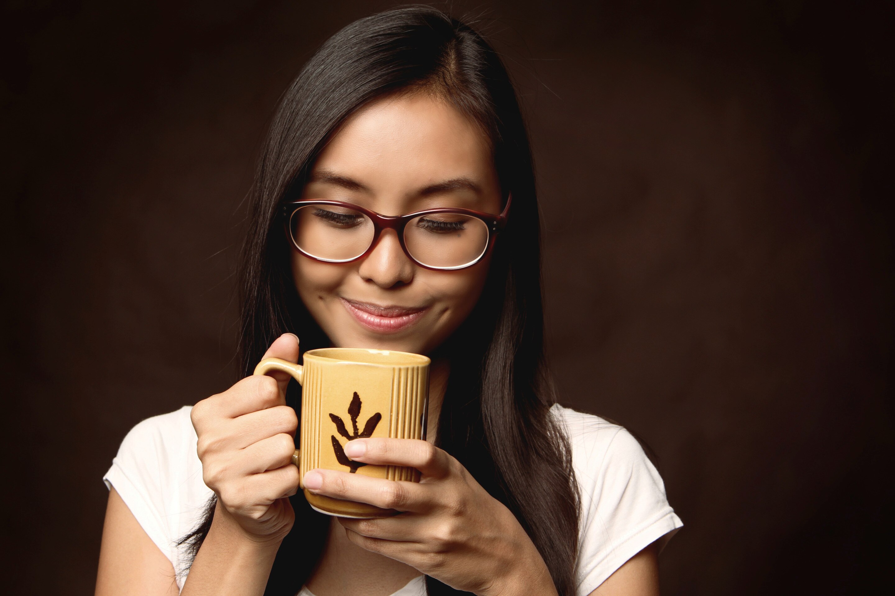 Asian woman with glasses drinking from a mug