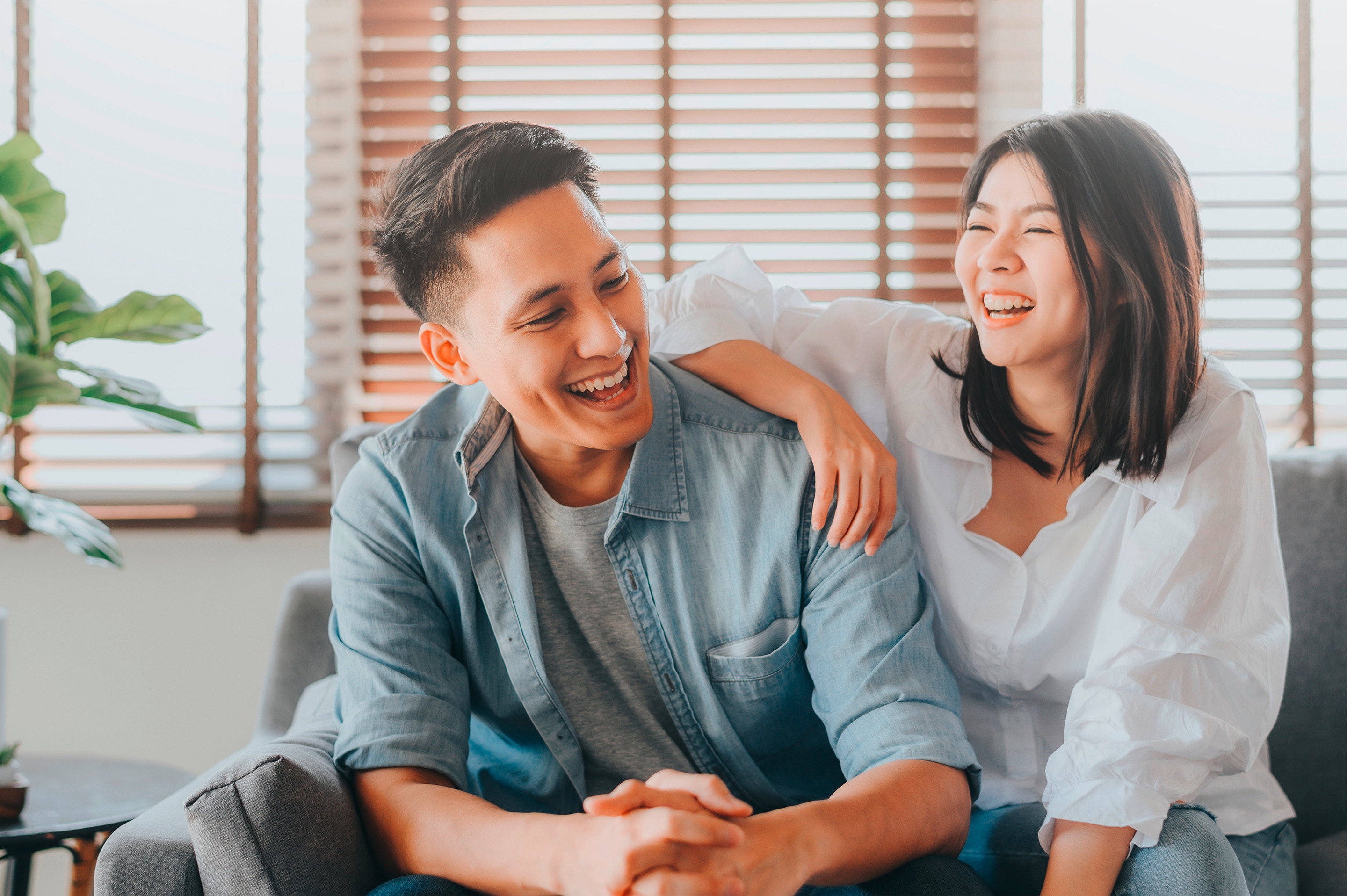 Pasangan pria dan wanita Asia sedang duduk bercanda sambil tertawa