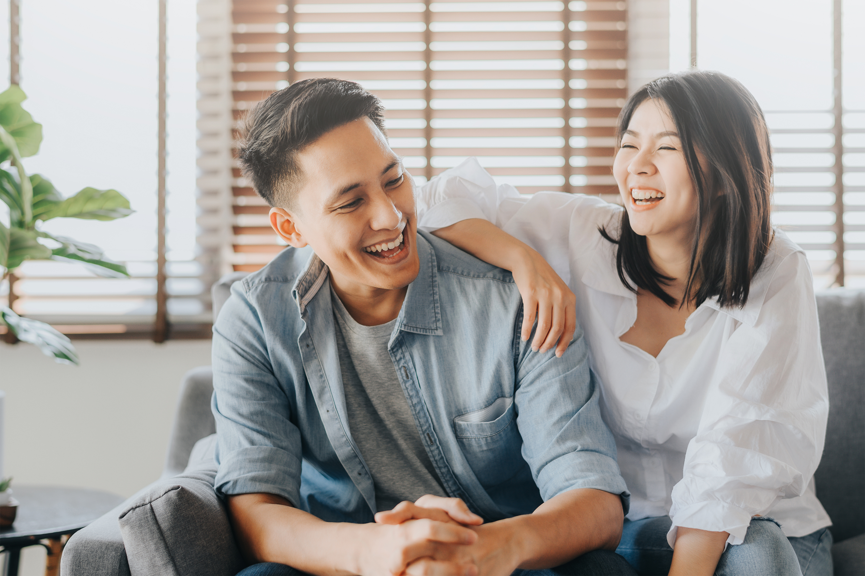 Pasangan pria dan wanita Asia sedang duduk bercanda sambil tertawa