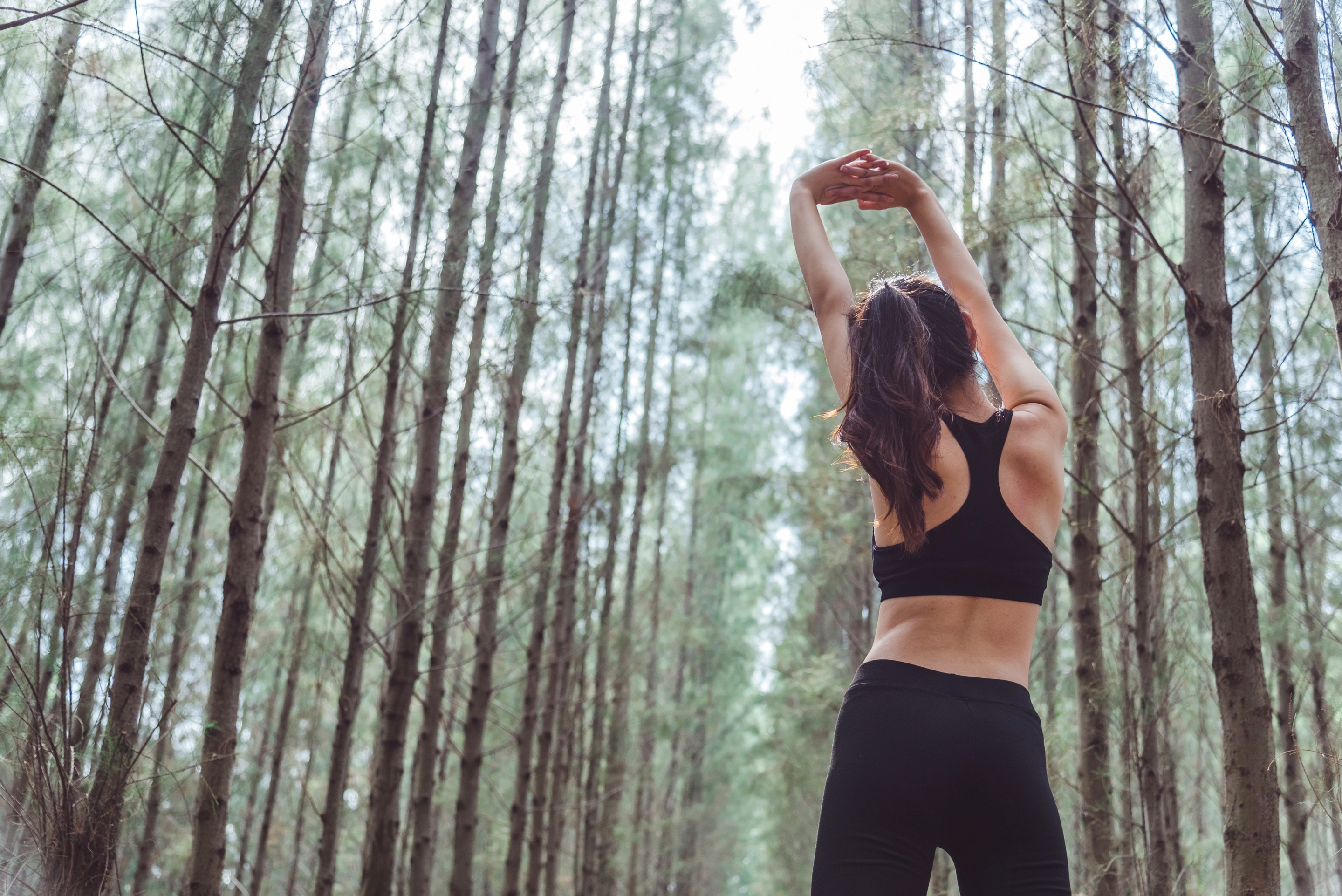An Asian woman in workout wear stretching her arms
