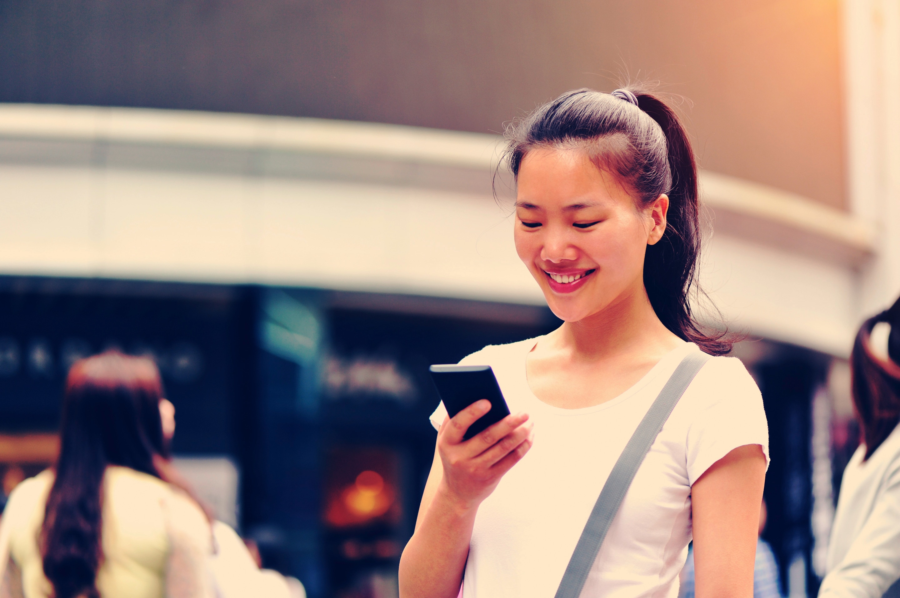 Asian woman wearing a ponytail and looking at her phone 