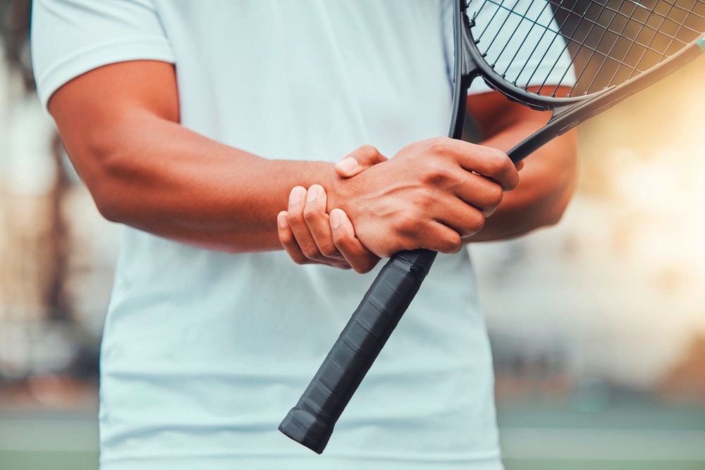 A tennis player gripping his wrist in pain.