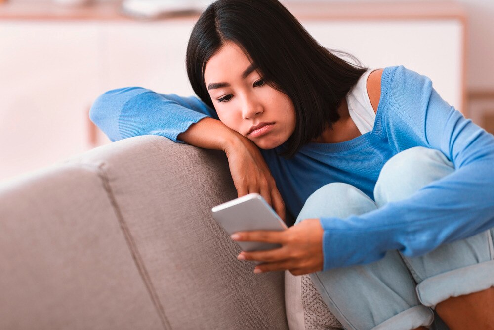 Woman with sad expression staring at her phone.