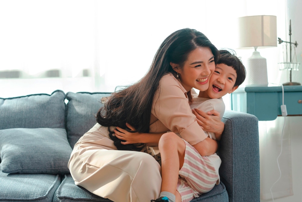 Mother hugging her young son while sitting on a sofa.