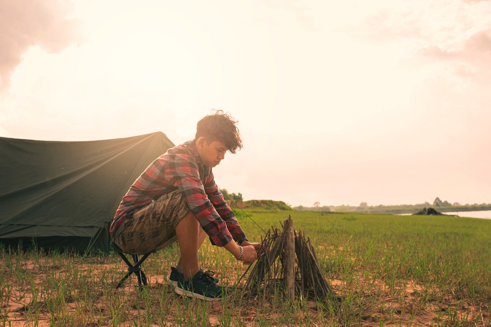 Asian camper trying to light a fire.