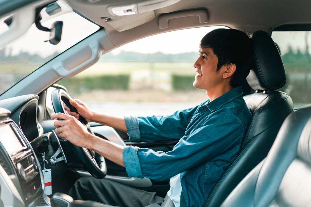 Man driving in his car while smiling.