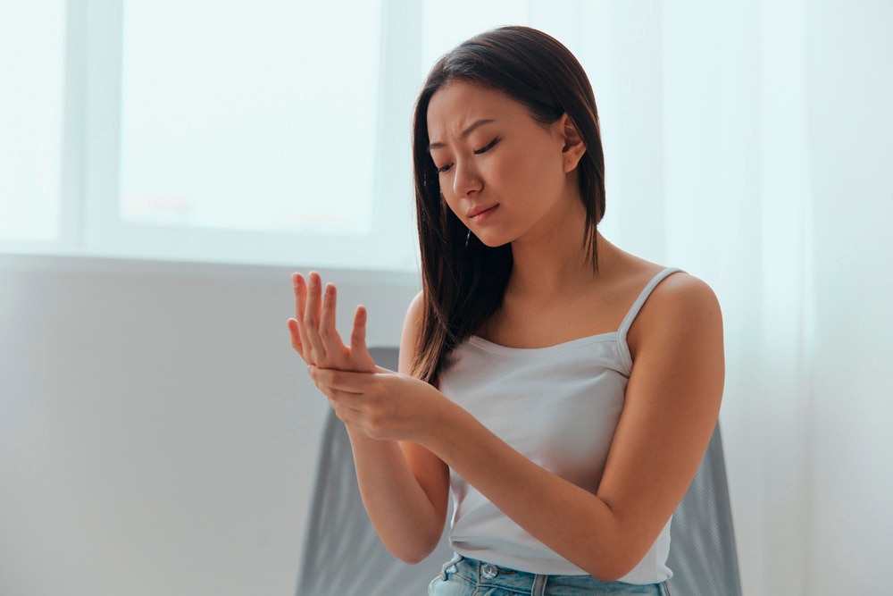 Woman scratching her itchy palm with a worried expression.
