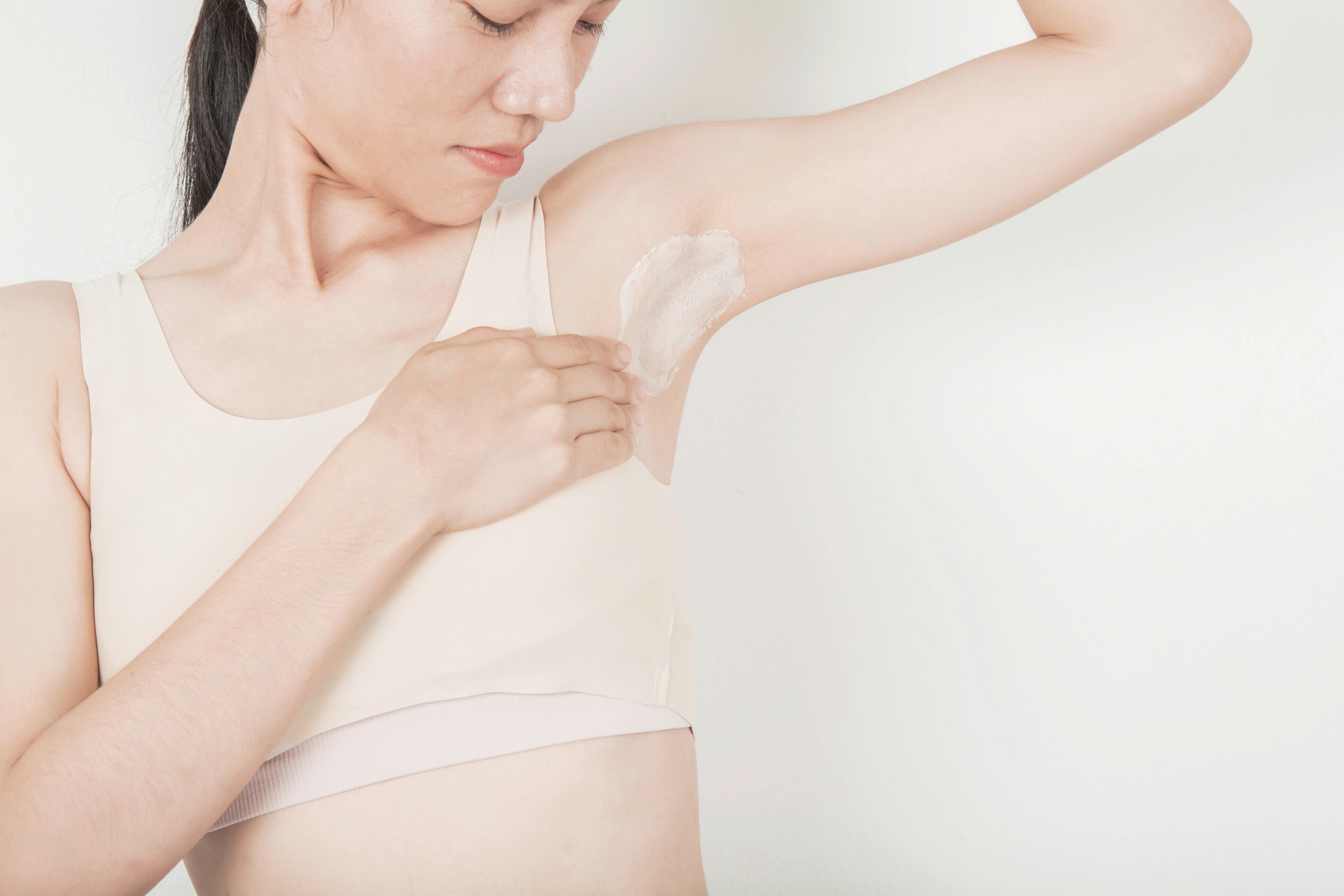 An Asian woman applying a scrub on her underarms 