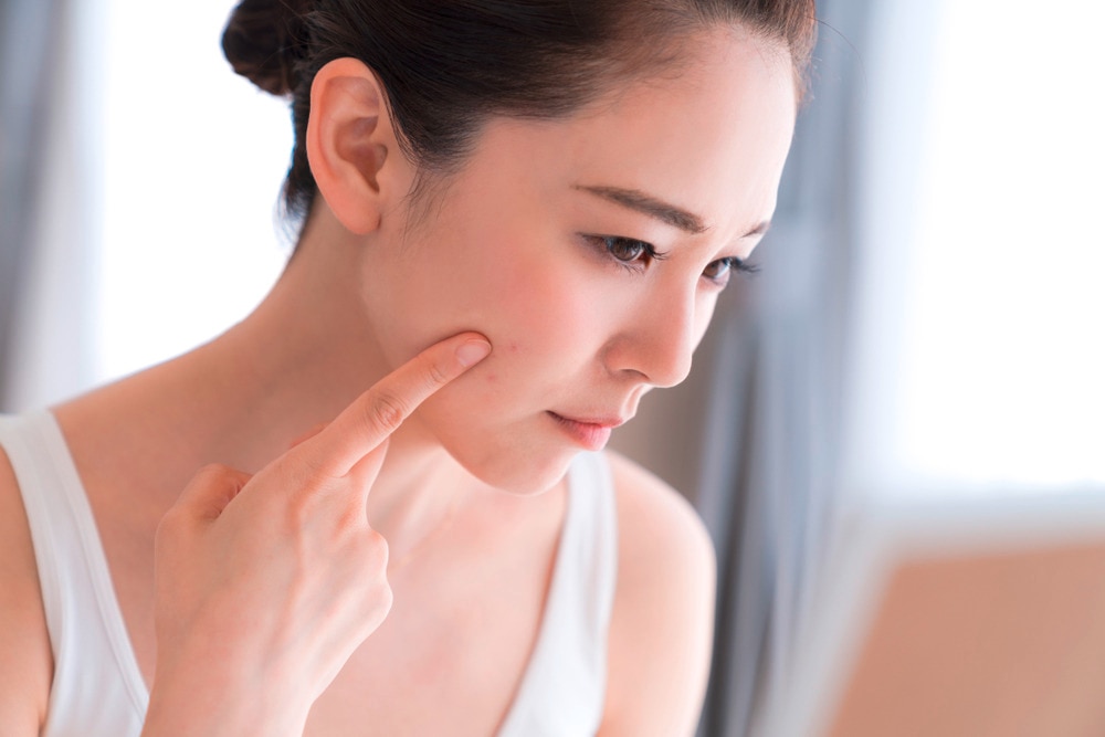 Cô gái búi tóc gọn gàng đang chỉ ngón tay trỏ lên má