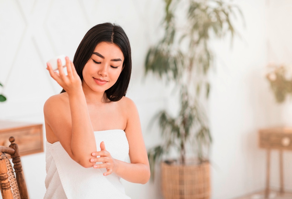 Woman applying lotion to her arm.