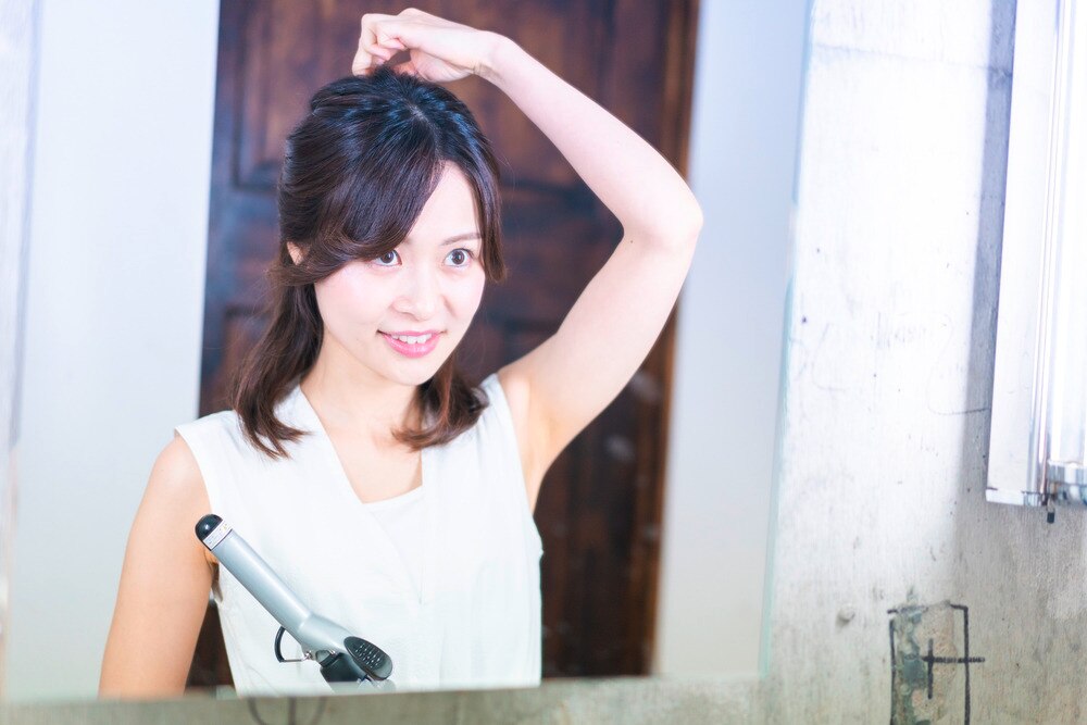 Woman sectioning her hair while holding a curling iron.