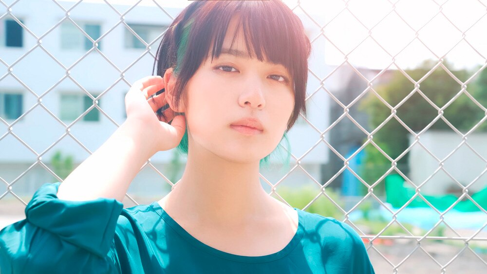 A portrait of woman with short hair and green streaks.