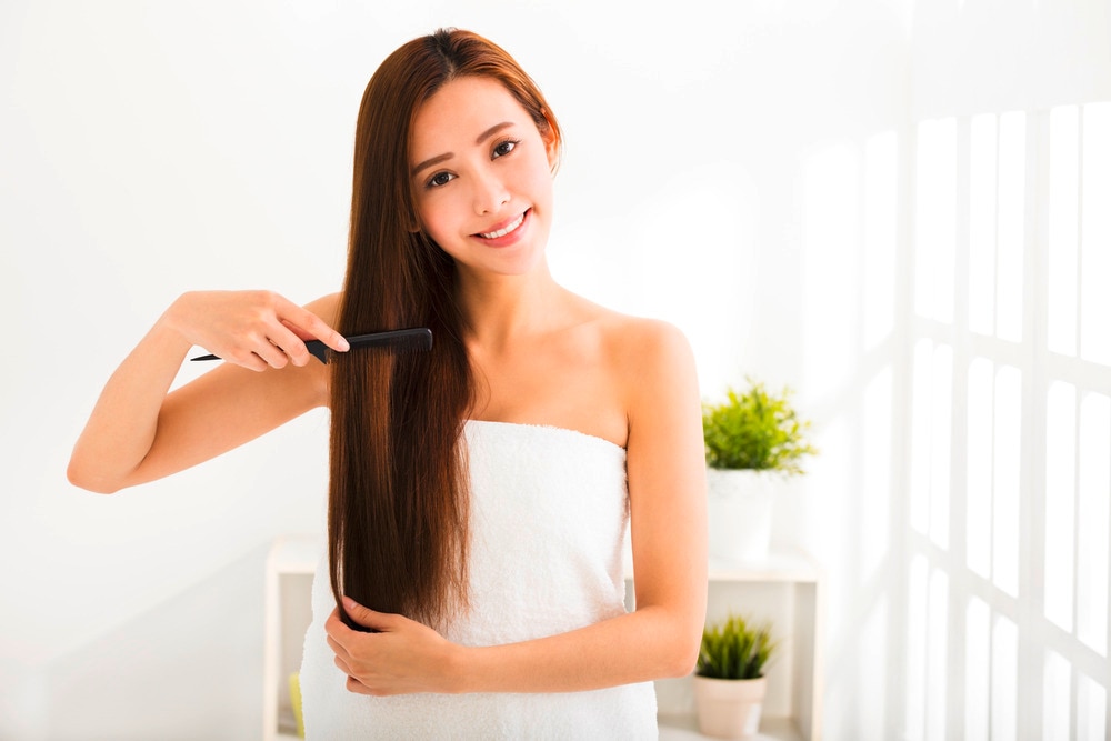 Woman brushing her long hair with a black comb.