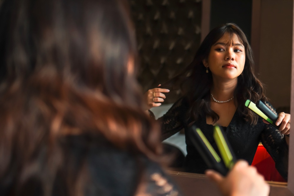 Woman curling her hair with a flat iron.