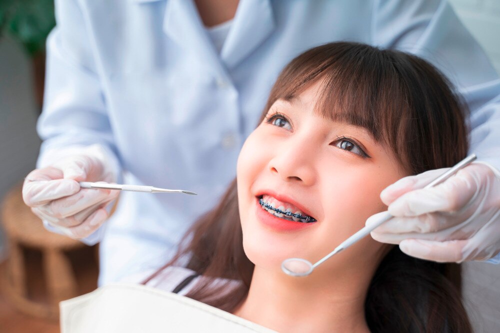 Woman with braces getting her teeth checked by dentist.
