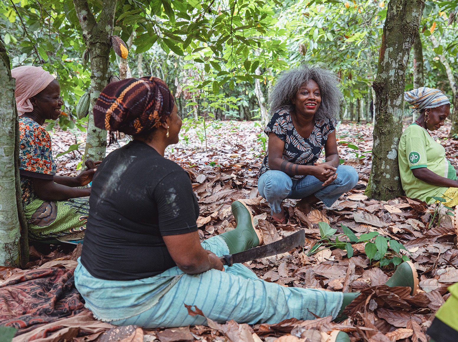 La créatrice de mode ivoirienne Rebecca Zoro dans une plantation de cacao avec des femmes de la communauté agricole