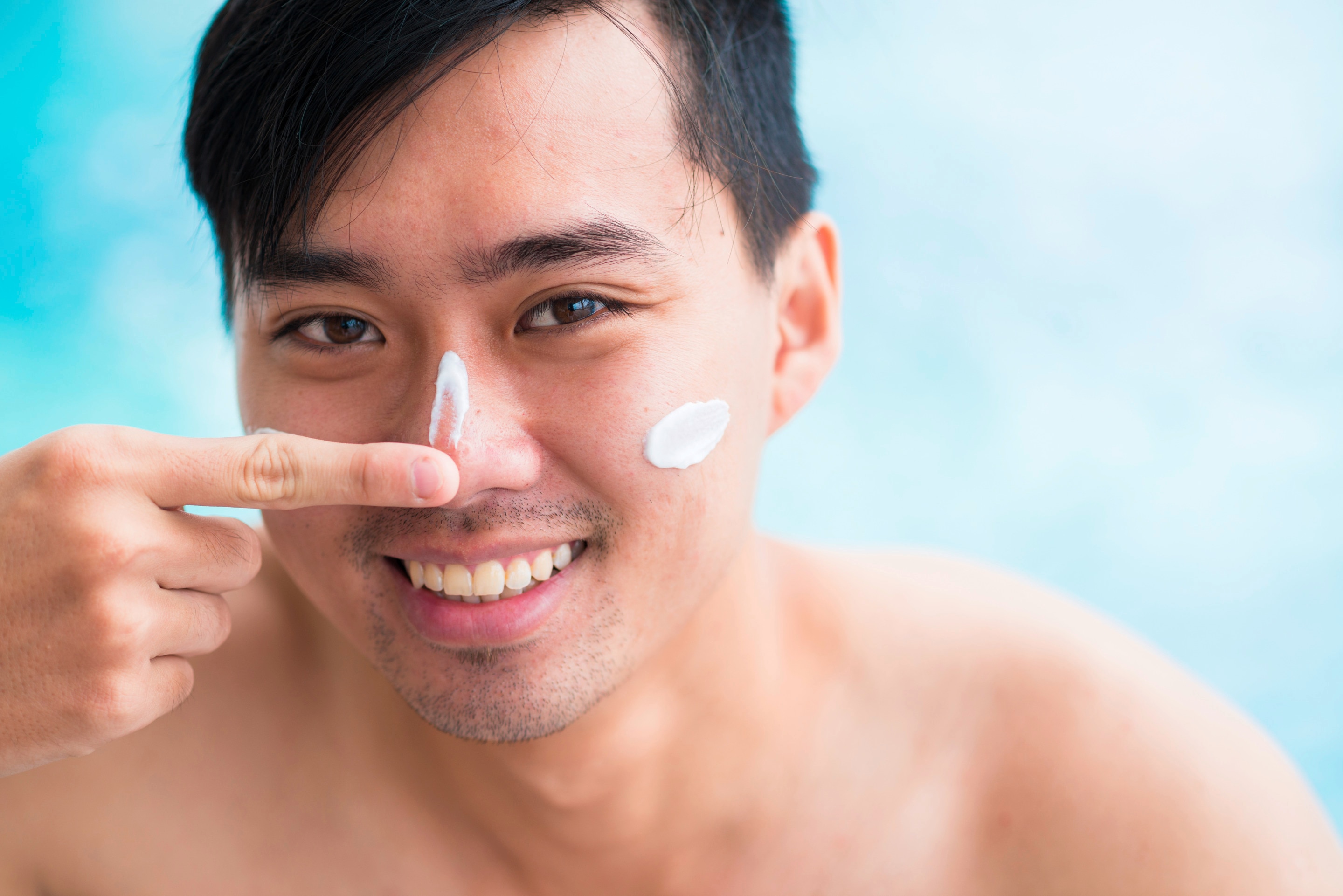 A smiling man applying sunscreen
