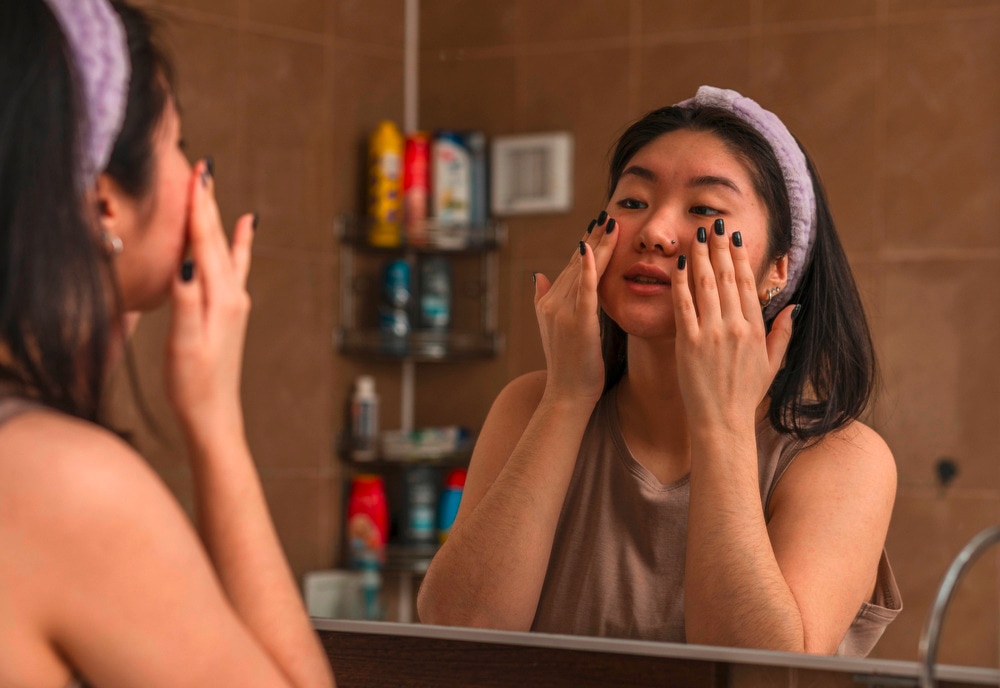 Woman applying serum onto her face with her fingers.
