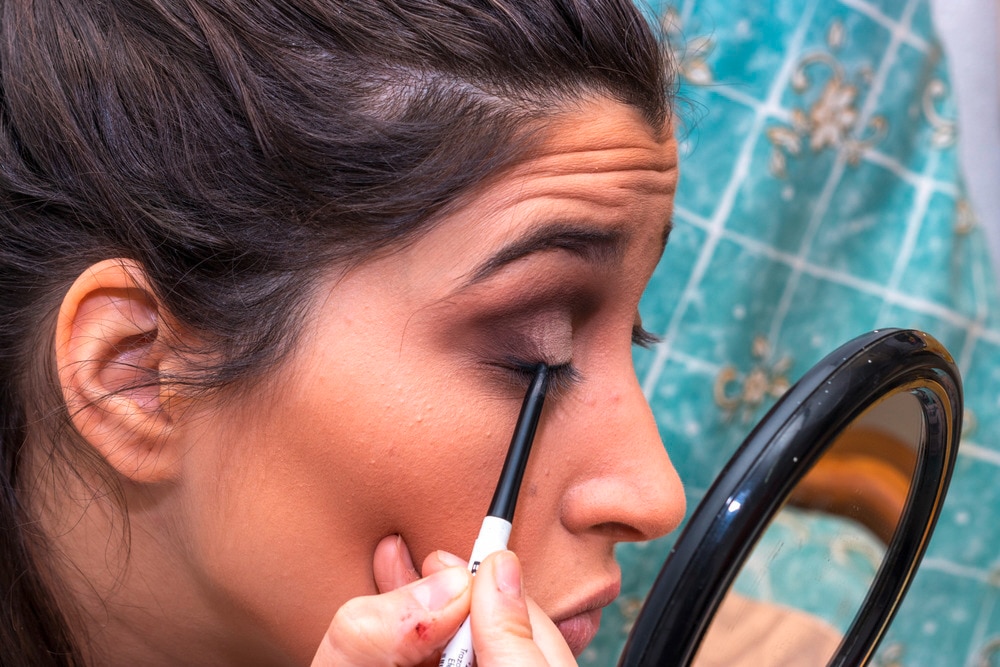 Woman applying dark powder eyeshadow.