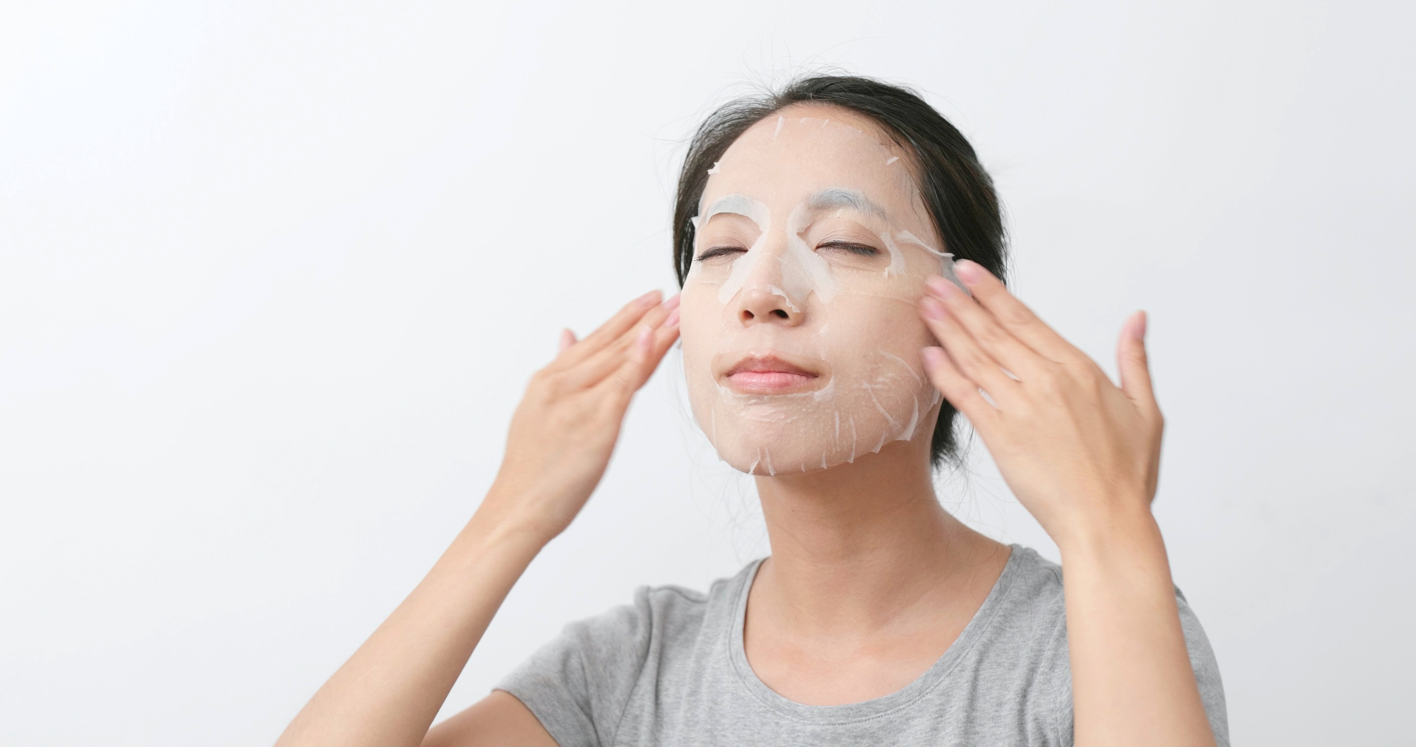 Asian woman putting on a sheet mask