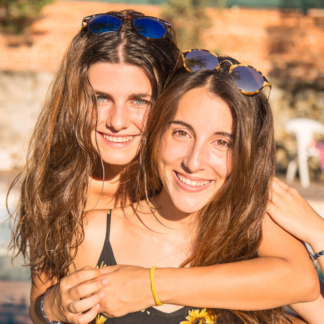 Two women smiling, one with smooth dry hair and the other with curly dry hair, near a car.