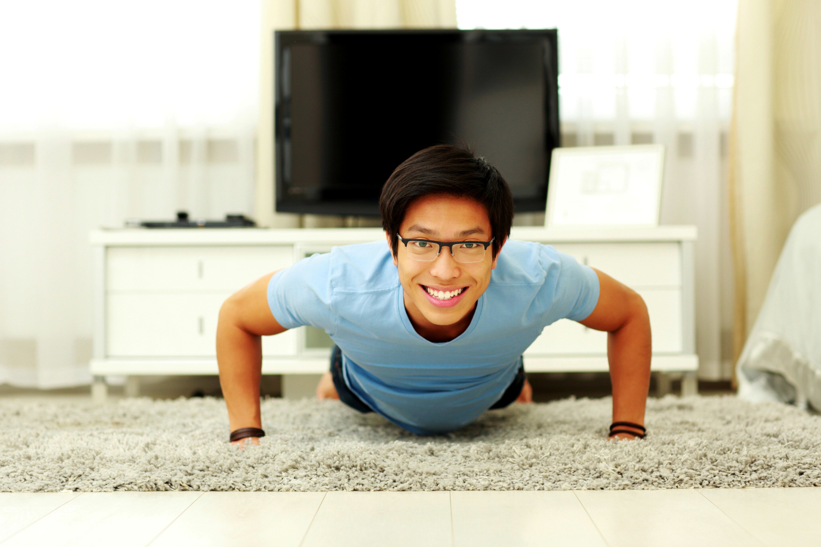 Smiling young man doing push ups at home