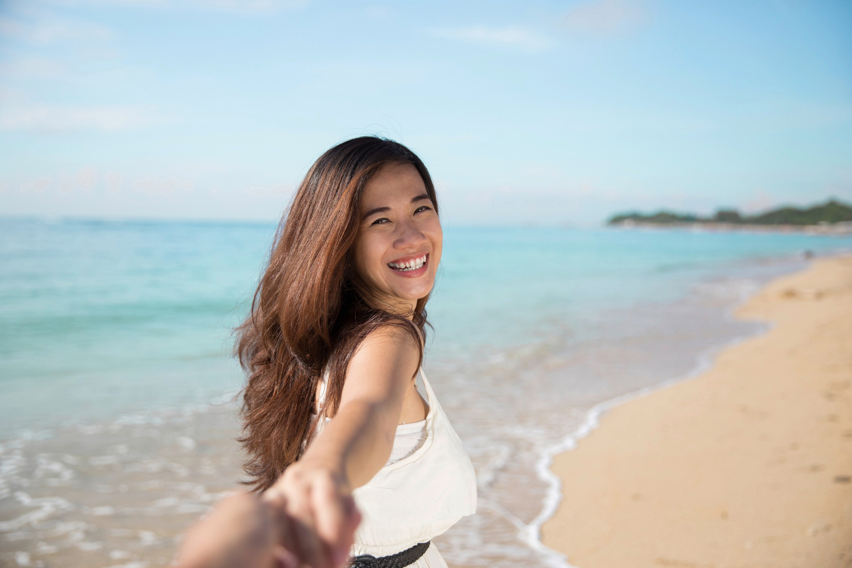A beautiful Asian woman with thick hair at the beach and looking back at the camera 