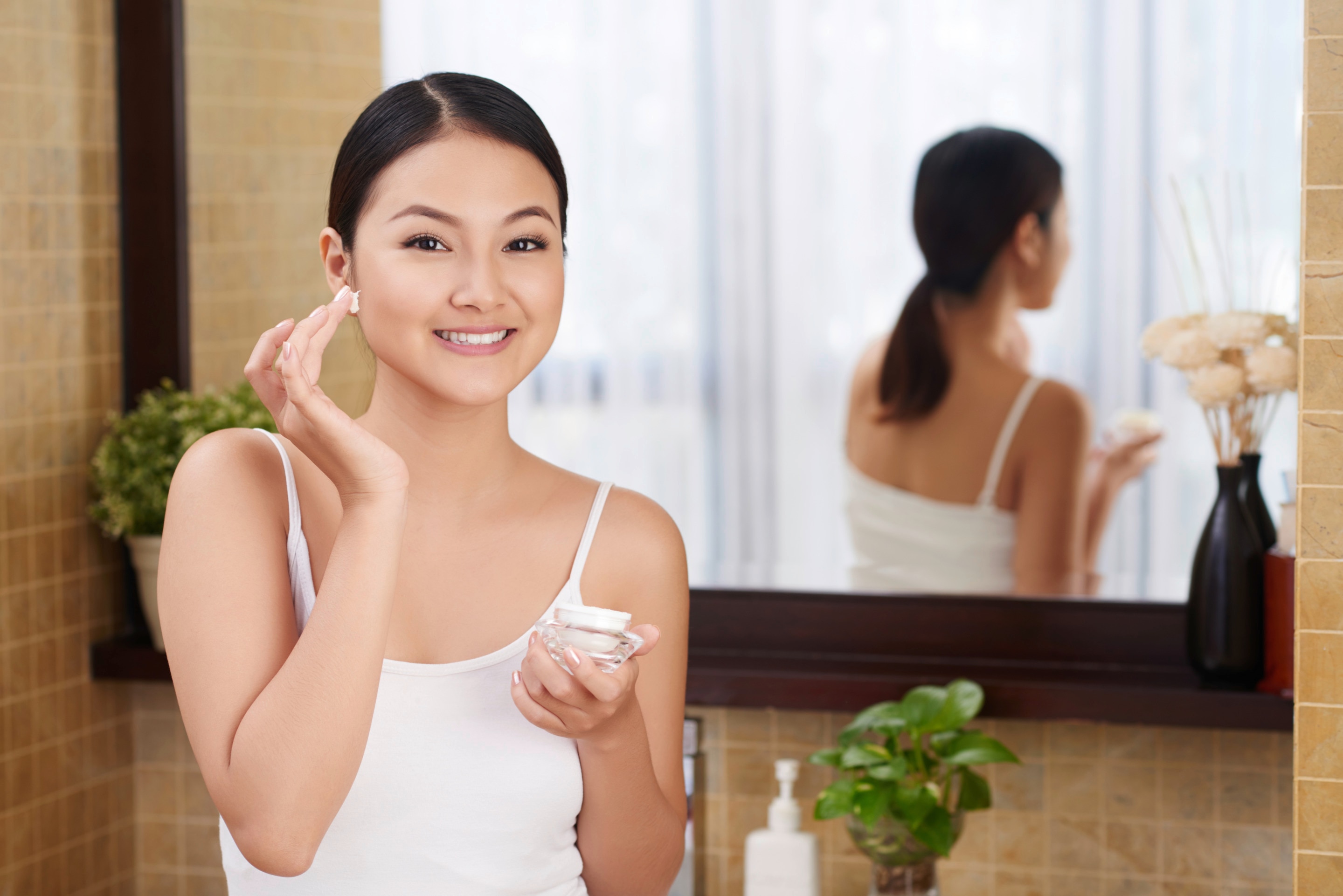 An Asian woman applying moisturizer