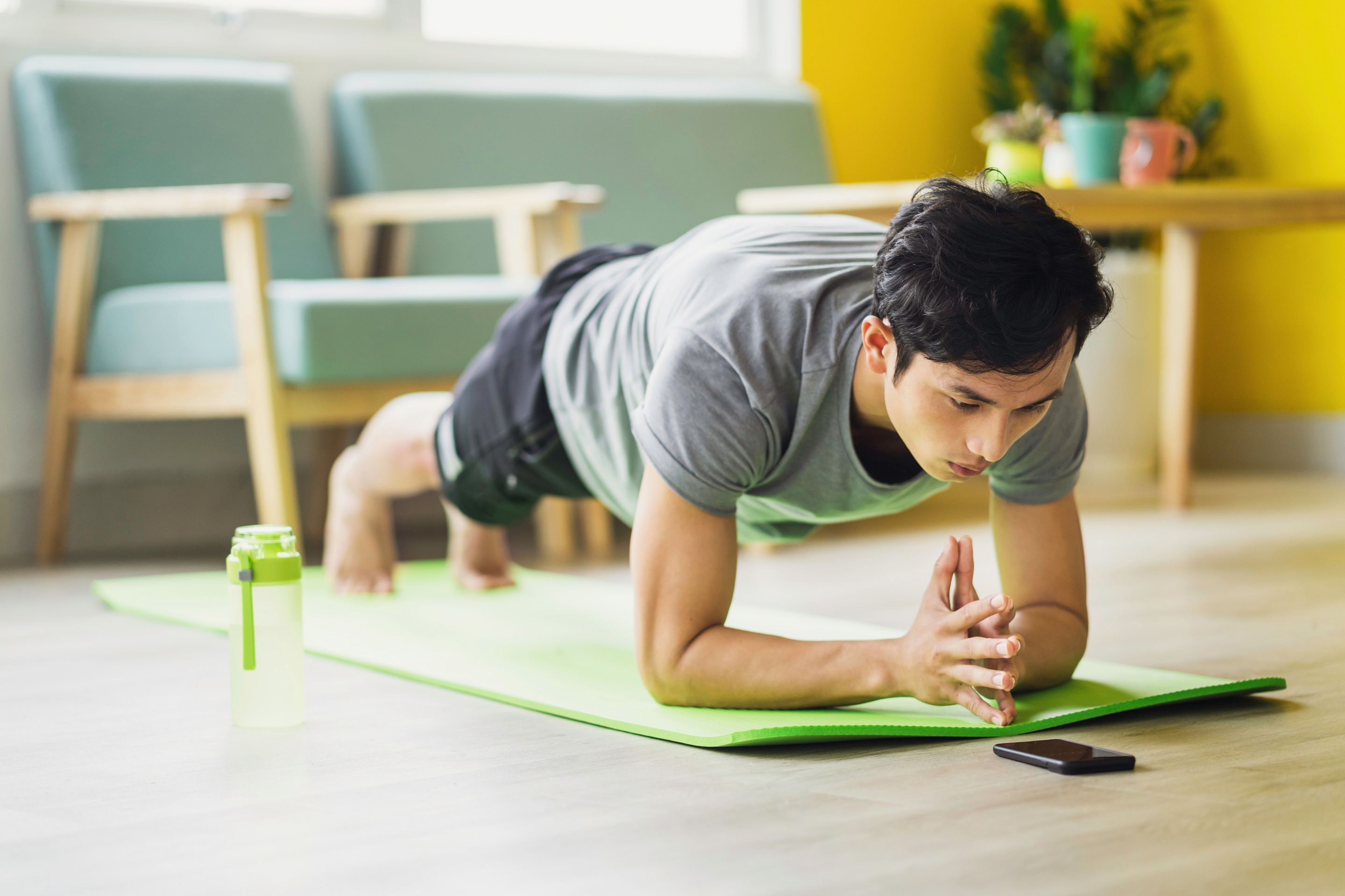 pria sedang melakukan gerakan workout di rumah berupa elbow plank