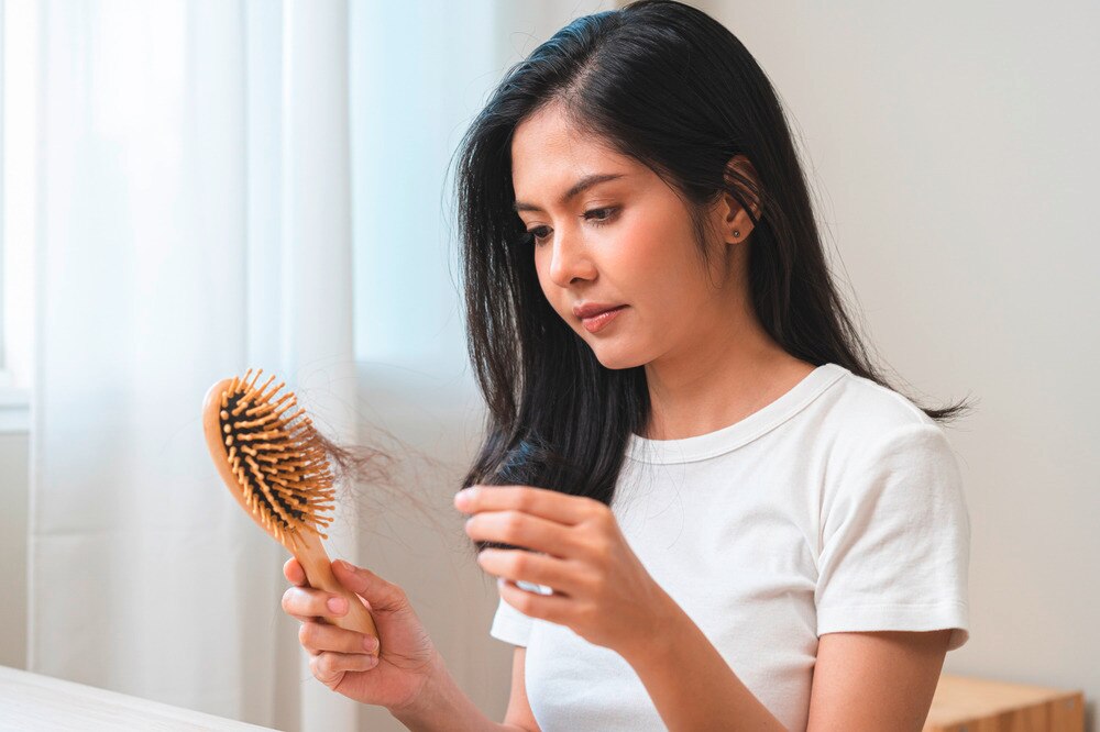 Woman removing hair strands stuck on a hairbrush.