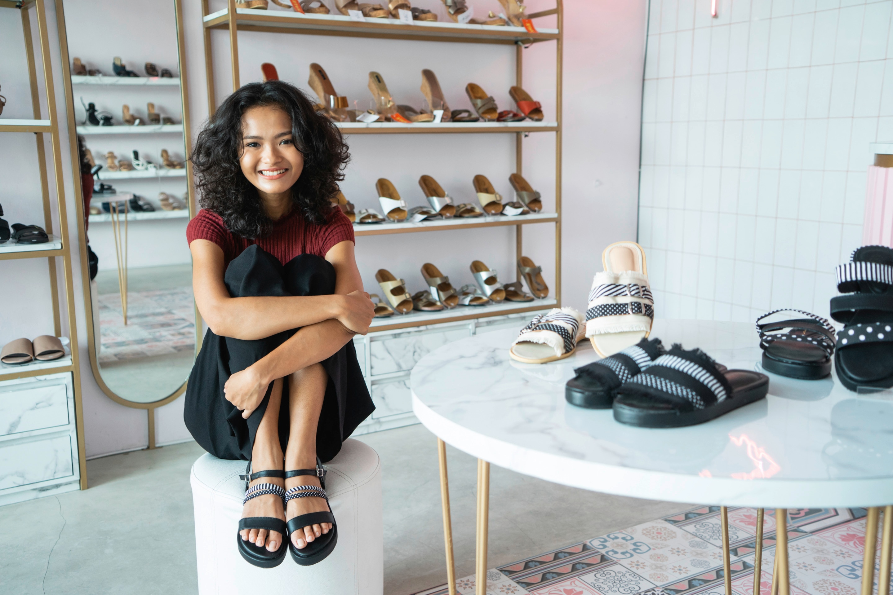 Asian woman with curly hair wearing black sandals in a shoe store