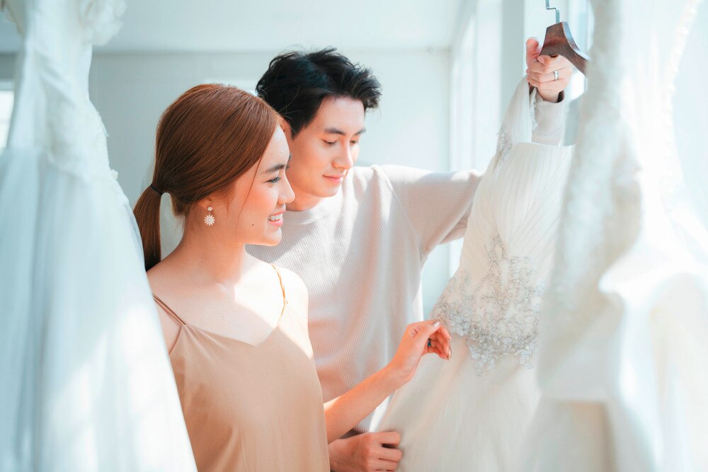 Asian bride and grooming looking at wedding gowns.